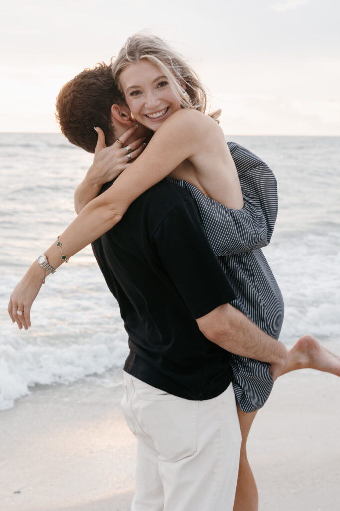 Couple taking engagement photo during surprise engagement on Naples beach in Florida. 