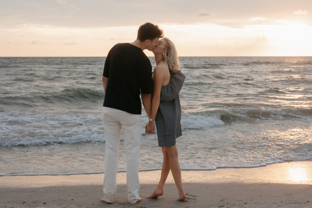 Couple taking engagement photo during surprise engagement on Naples beach in Florida. 