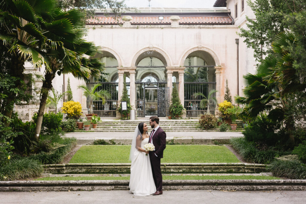 Couple posing in front of the main house at Vizcaya Museum and Gardens during their wedding day. 