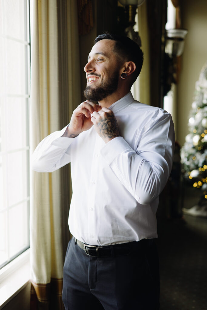 Groom looking out the window while getting ready for his wedding at The Club at the Strand in Naples, Florida. 