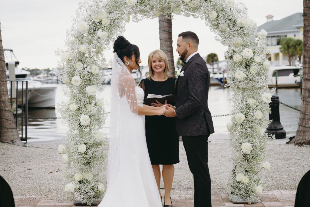 Bride and groom hold hands during a wedding ceremony at Naples Bay Resort in Naples, Florida. 