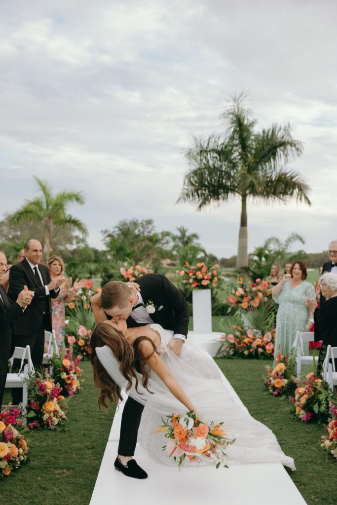 bride and groom kissing at their ceremony after getting married, surrounded by wedding guests celebrating, during their florida wedding