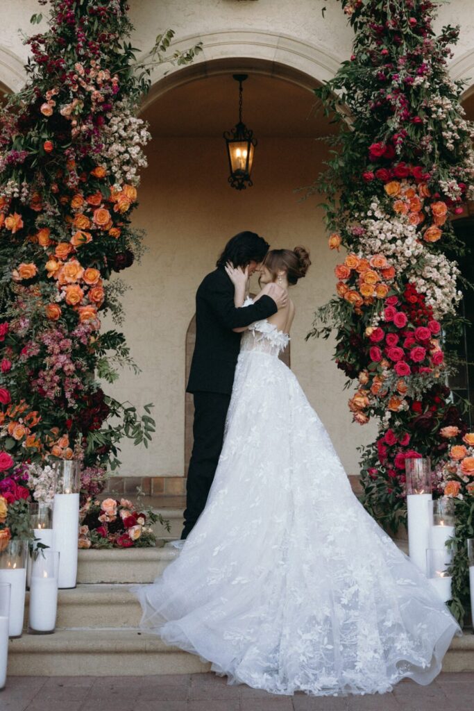 bride and groom sharing an intimate stare into each other's eyes during their portrait session while surrounded by orange, white, and red flowers at their florida wedding venue