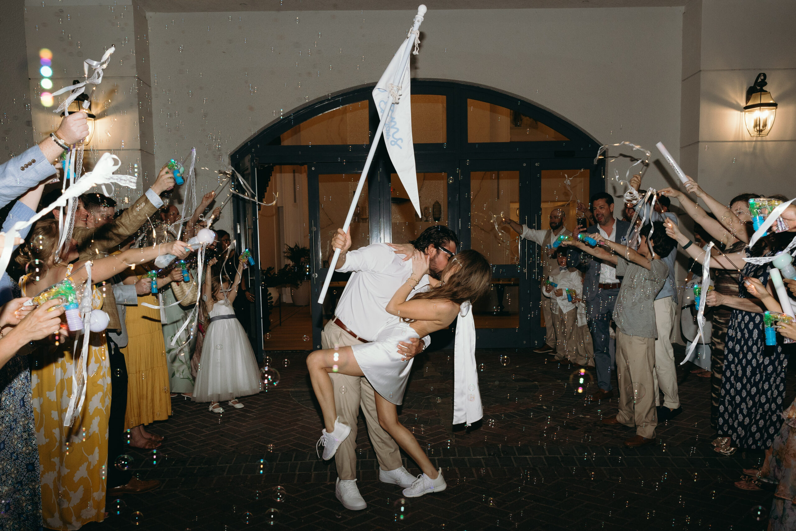 groom dipping bride for a kiss while they exit their reception held at one of the best outdoor wedding venues in naples, fl
