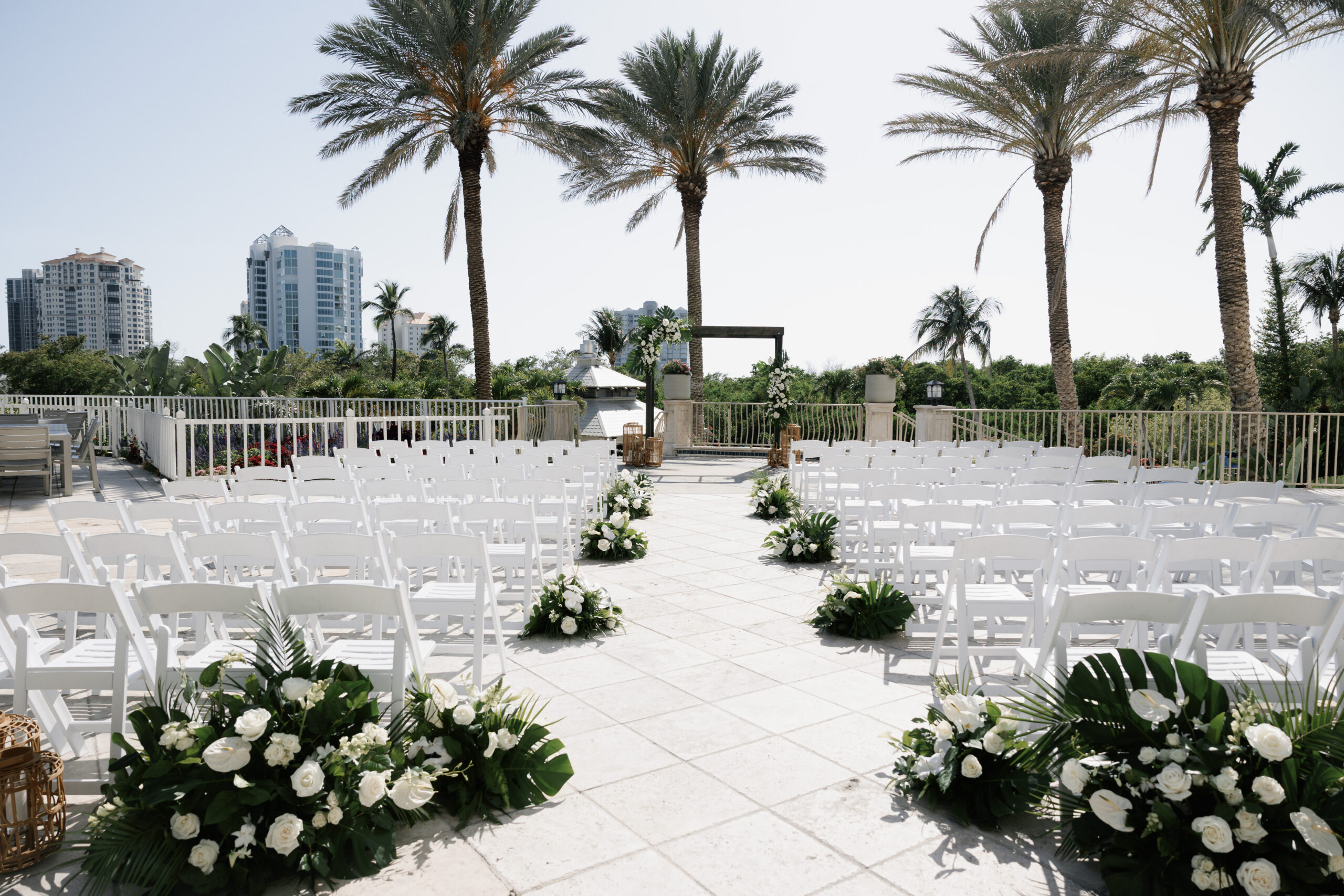 outdoor ceremony drenched in white with green floral arrangements created by one of the best naples wedding florists