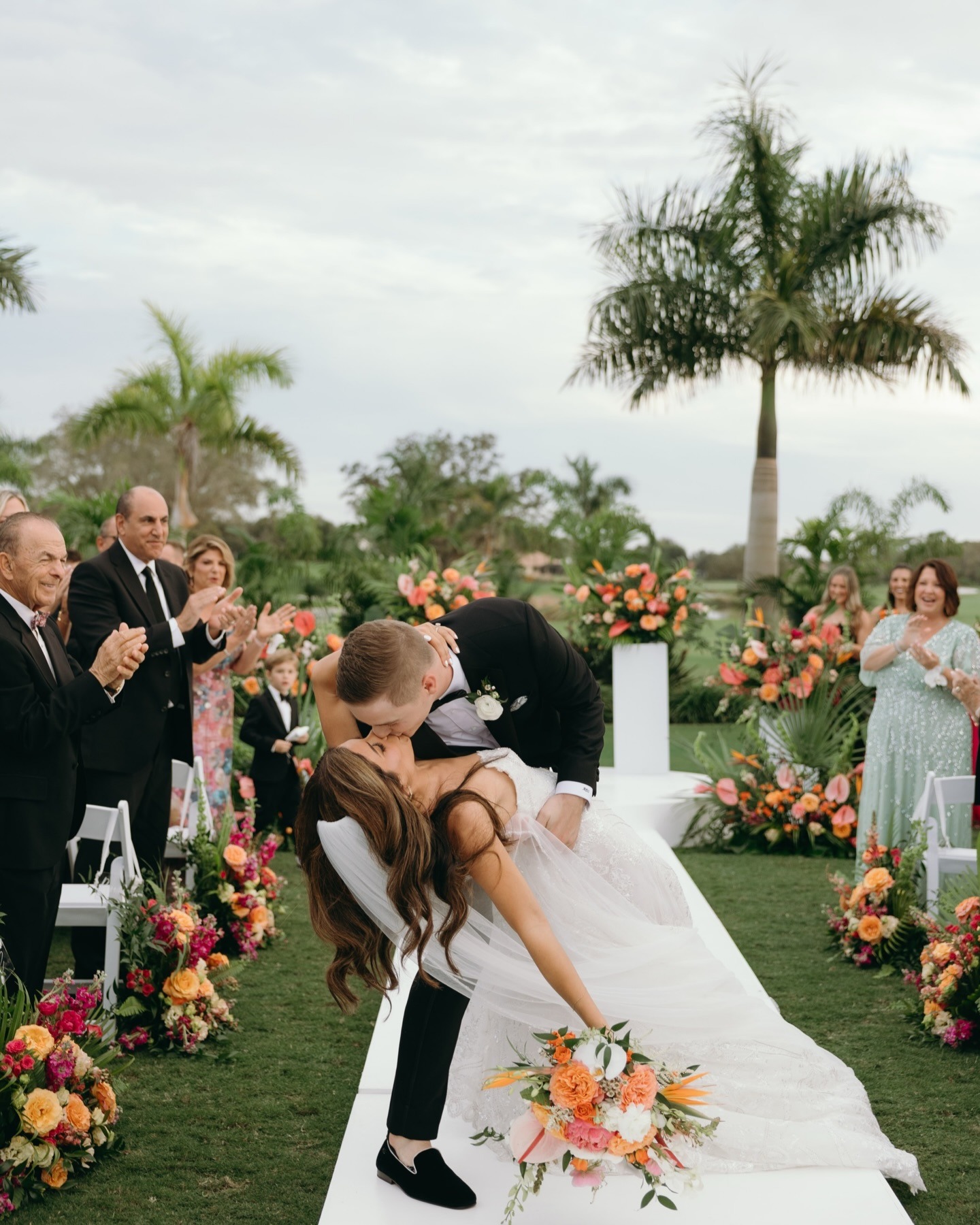 bride and groom kissing after their wedding ceremony surrounded by bold flower arrangements created by one of the top naples wedding florists