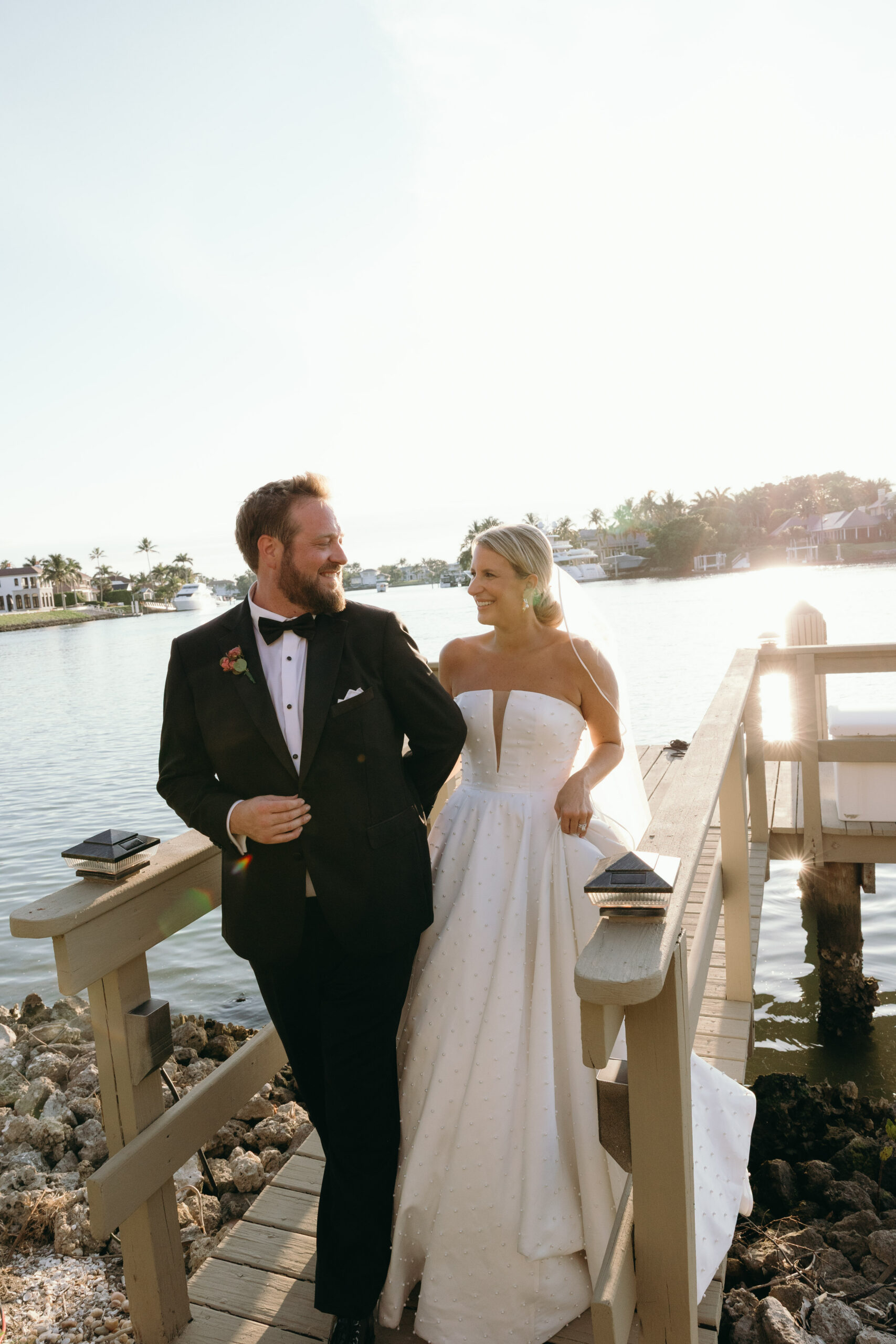 portrait of a bride and groom walking on a wooden bridge during their naples wedding